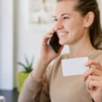 Eine Frau telefoniert und hält dabei eine Visitenkarte